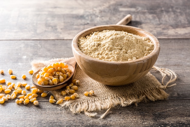 Corn flour in bowl on wooden table