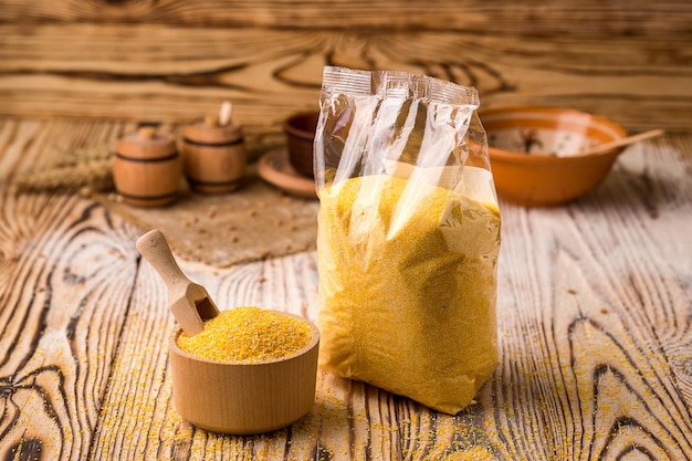 Corn groats in packing and bowl on a wooden background Healthy dietary cereals concept