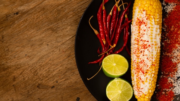 Corn on plate with limes and peppers