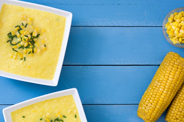 Corn soup in bowl on blue wooden surface