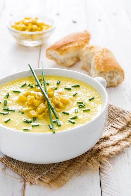 Corn soup in bowl on white wooden