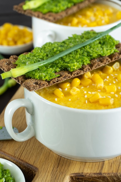 Corn soup with fresh garlic pate in white bowl Healthy food on wooden background Vegan cuisine