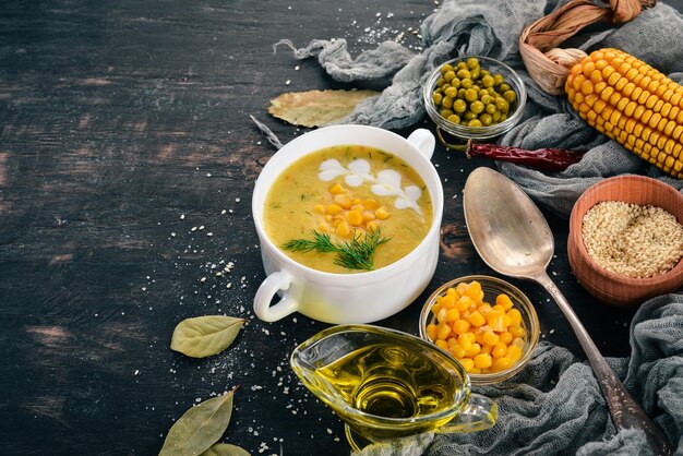 Corn soup with fresh vegetables in a bowl Healthy food On a black wooden background Top view Copy space for your text