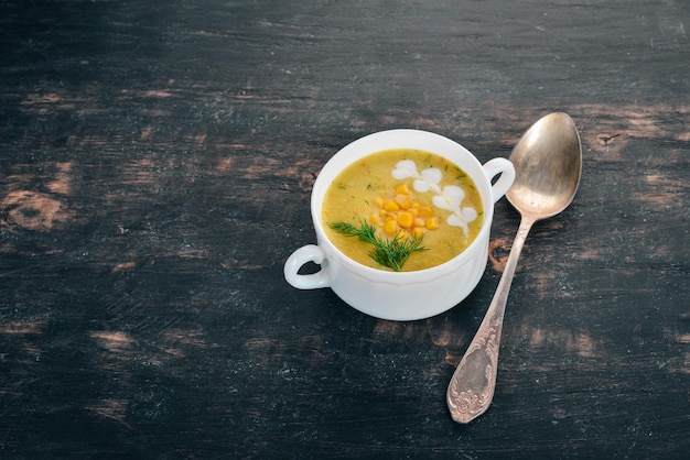 Corn soup with fresh vegetables in a bowl Healthy food On a black wooden background Top view Copy space for your text