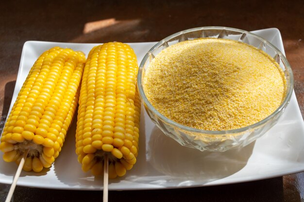 Corn on a stick in a plate and cornmeal