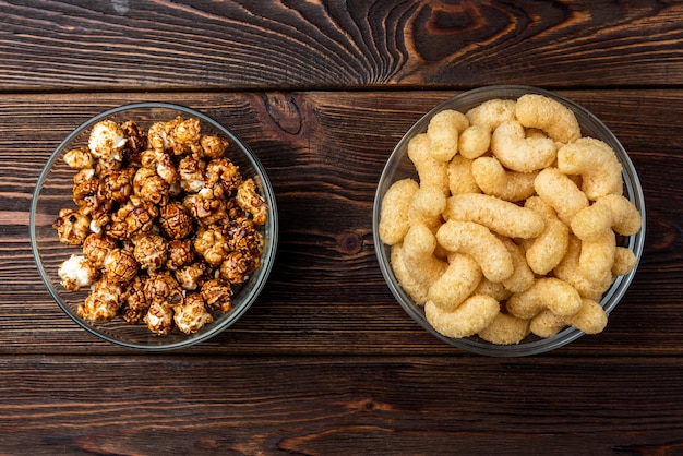 Corn sticks and popcorn on dark wooden background.