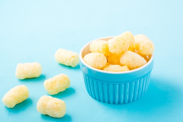 Corn sticks in powdered sugar in a bowl on a blue table. Children treat