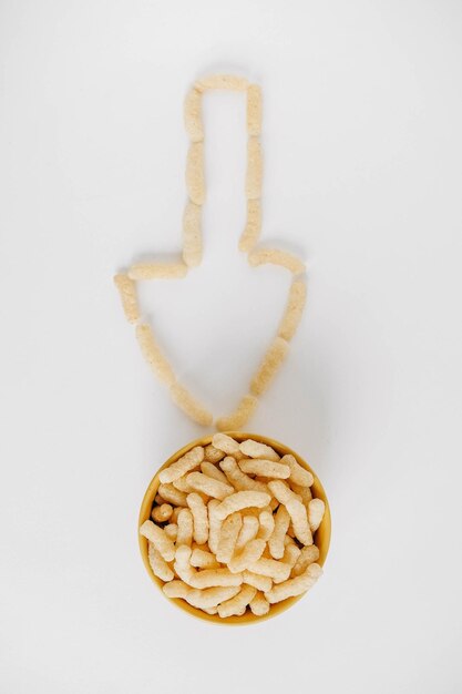 Corn sticks in a yellow bowl scattered in the shape of an pointer on a white background