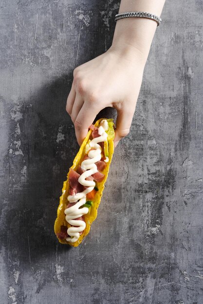 Corn tacos with tuna on a concrete table and a female hand