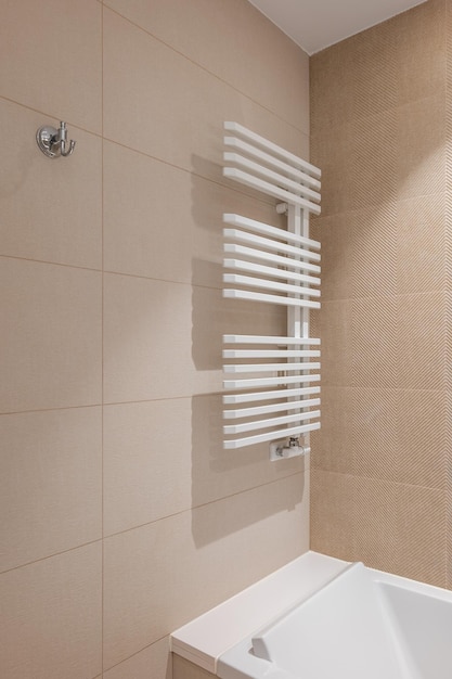 Corner of bathroom in the center with a white heating radiator on the wall for drying towels the