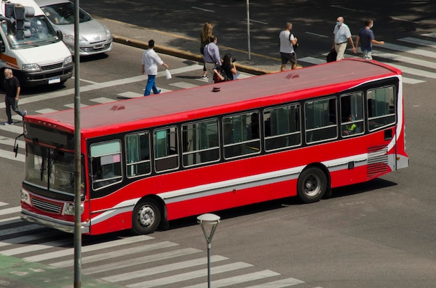 Foto un angolo della città di buenos aires con un collettivo e persone che attraversano la strada