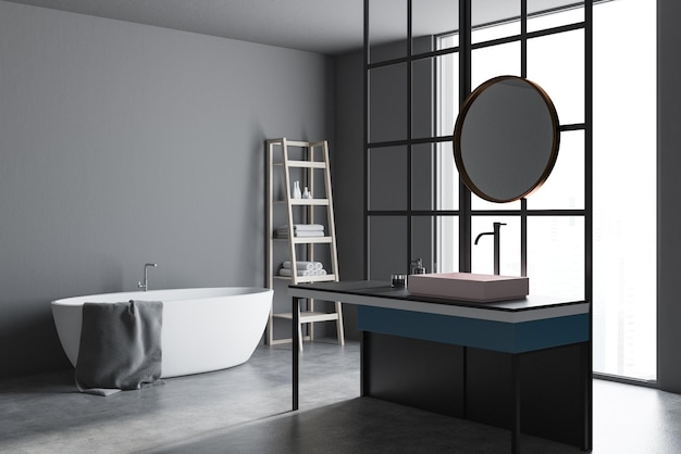 Corner of a modern bathroom with loft window, a concrete floor, a sink with a round mirror and a white bathtub. Gray walls. 3d rendering mock up