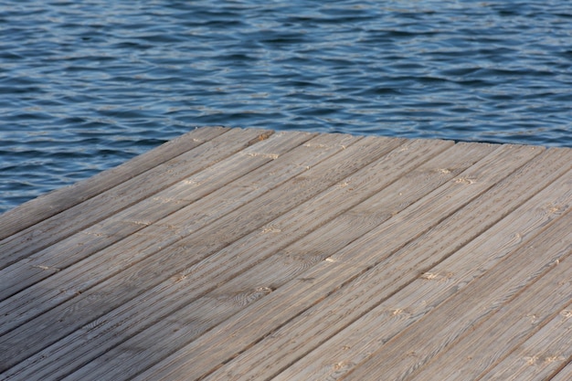 Corner of a platform made of wooden planks against the background of water