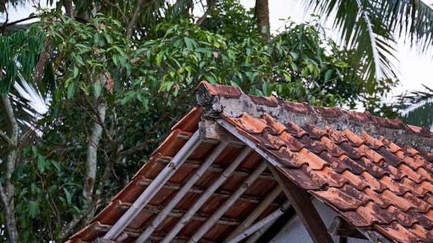 The corner of the triangular facade of the tiled roof of the house