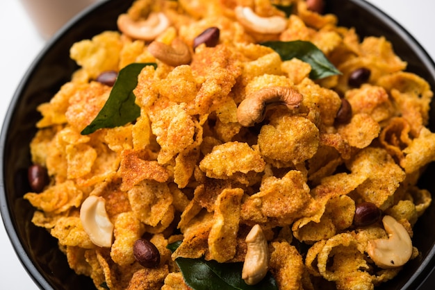 Cornflake Chivda of Corn Chiwda geladen met pinda's en cashewnoten. Geserveerd in een kom. selectieve focus