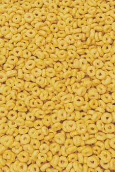 Sfondo e consistenza dei fiocchi di mais vista dall'alto scatola di cereali con anelli di miele per la colazione del mattino