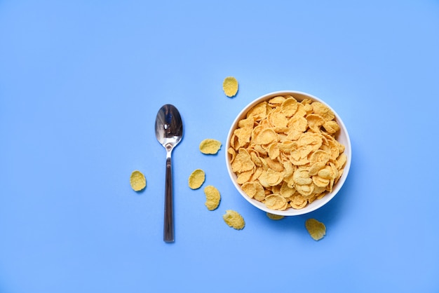 Cornflakes in bowl on blue  and spoon for cereal healthy food 