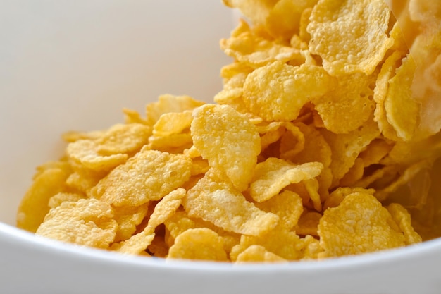 Cornflakes cereal spilling out of a plastic bag in a white bowl