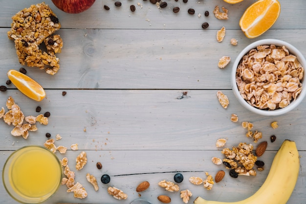 Foto cornflakes in kom met fruit en sap op tafel