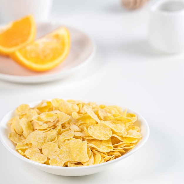 Cornflakes kom snoepjes met melk en sinaasappel op witte achtergrond close-up vers en gezond ontbijt ontwerpconcept