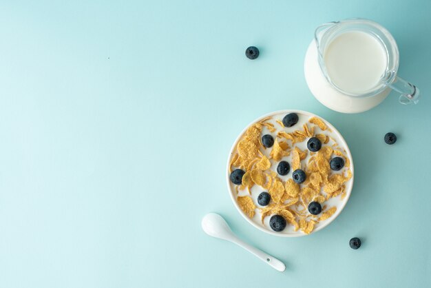 Cornflakes met melk en bosbessen op een blauwe achtergrond