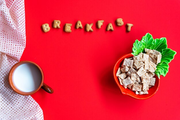 Cornflakes ontbijtgranen in kom en kopje melk op rood