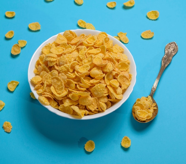 Cornflakes in a white ceramic plate and an iron spoon 