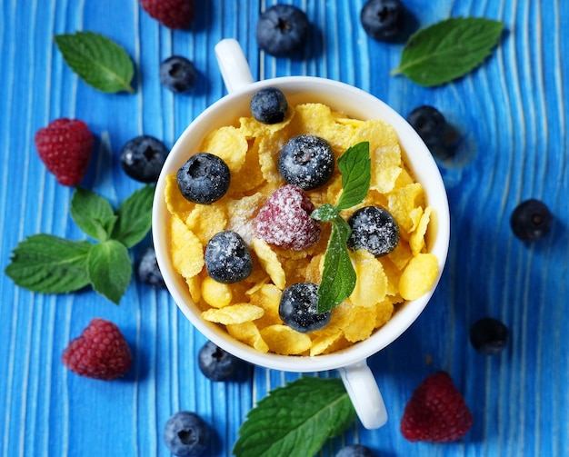 Cornflakes with berries raspberries and blueberries on blue wooden background top view