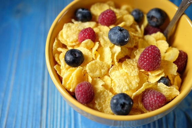 Cornflakes with berries raspberries and blueberries on blue wooden background