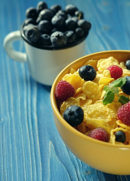 Cornflakes with berries raspberries and blueberries on blue wooden background