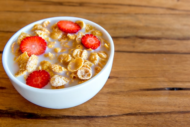 Cornflakes with milk and pieces of strawberry, healthy breakfast.