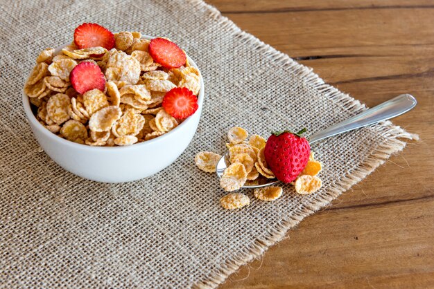 Cornflakes with milk and pieces of strawberry, healthy breakfast.