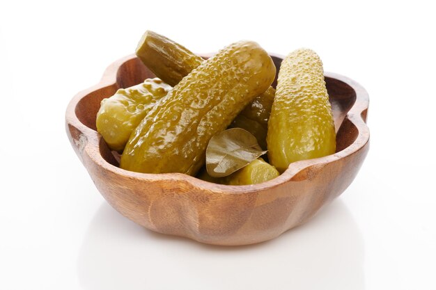 Cornichons pickled cucumbers in wooden bowl over white