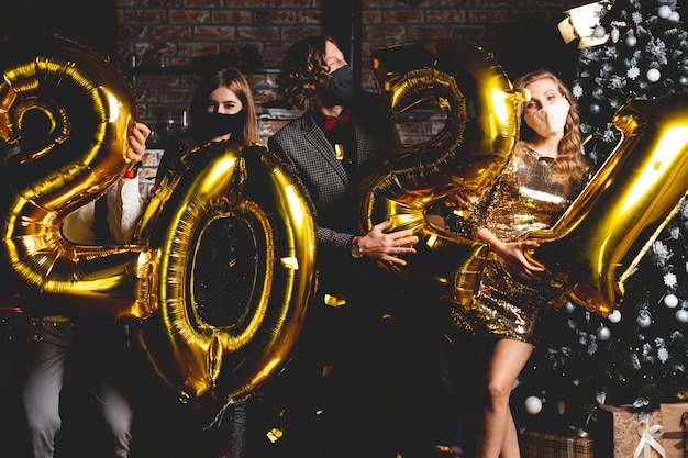 Photo corona virus pandemic. party, people and new year holidays concept - women and men in protective medical mask celebrating new years eve 2021