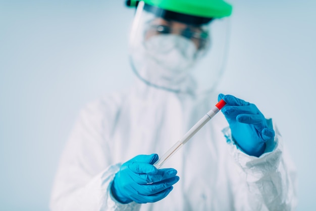 Corona virus test - medical worker in white protective suite with swab sample for pcr dna testing