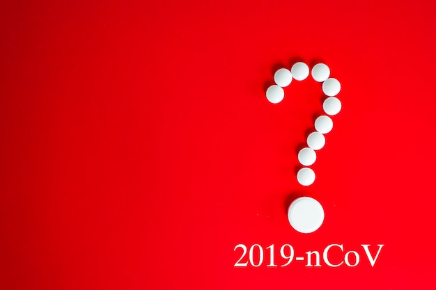 コロナウイルス2019-ncovの新しいコロナウイルスの概念は、アジア風邪の発生と、危険なインフルエンザ株のパンデミックとしてのインフルエンザのコロナウイルスに責任があります。赤に疑問符の形の白い錠剤。