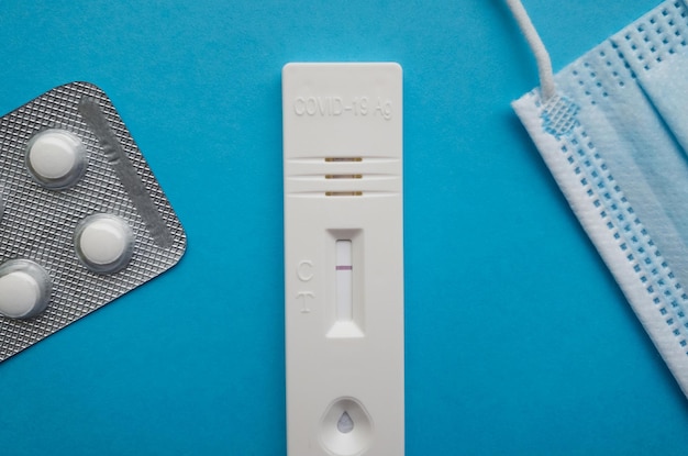 Coronavirus antigen test with a negative result on a blue bright background next to a thermometer a