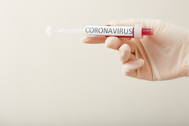 Coronavirus bloedonderzoek resultaat, bloed besmet met coronavirus in vacuüm reageerbuis in de hand van de arts, tekst Coronavirus.