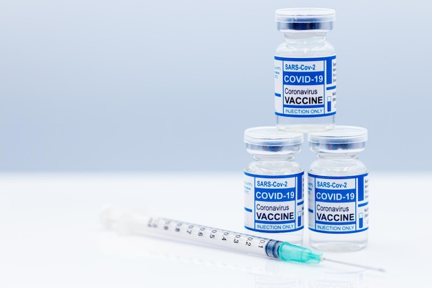 Coronavirus (COVID-19) covid vaccine dose bottle and medical needle syringe with  space for text.