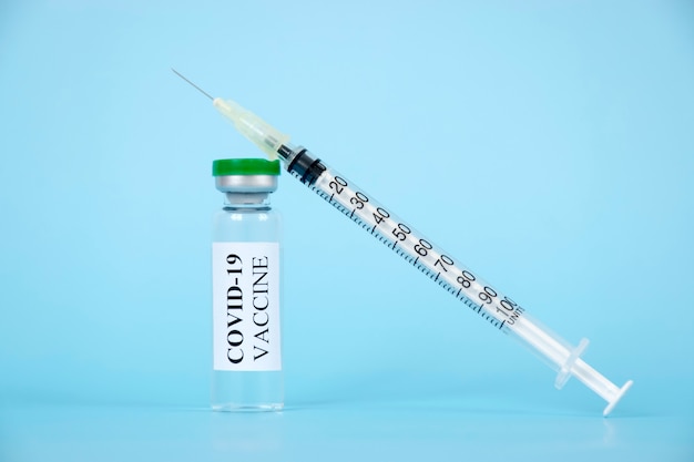 Coronavirus COVID-19-vaccin in glazen fles en spuit voor injectie op blauwe achtergrond.