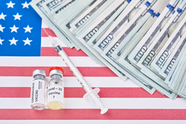 Coronavirus, covid-19 vaccine against background of flag of USA and money disease preparing for human clinical trials vaccination shot, medicine concept.