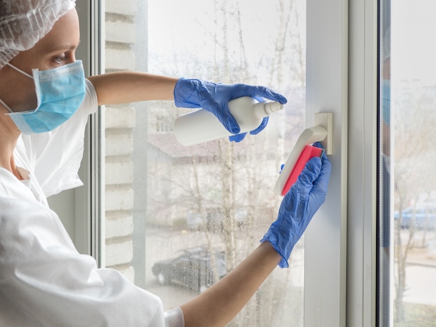 Coronavirus disinfection. People in making disinfection on windows. Doctor in rubber gloves disinfects windows handle with disinfectant and sponges