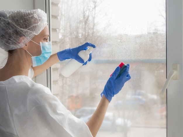 Coronavirus disinfection. People in making disinfection on windows. Doctor in rubber gloves disinfects windows with disinfectant and sponges