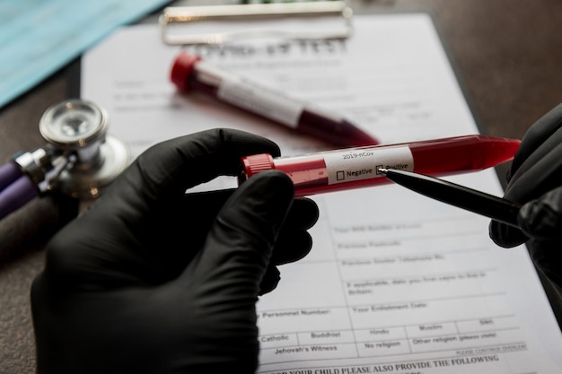 Coronavirus examination with positive result on a blood tube on a background of registration form