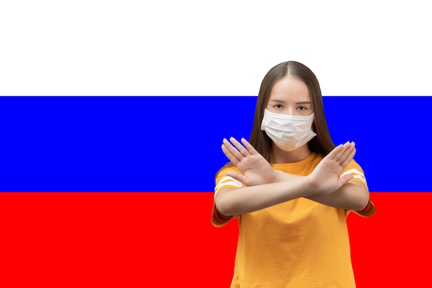 coronavirus in Rusland Meisje met antibacterieel medisch masker toont gekruiste handen op de achtergrond van de vlag