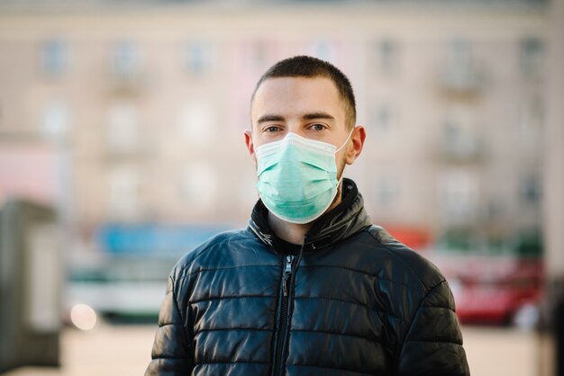 Coronavirus. Jonge mens in stadsstraat die gezichtsmasker draagt beschermend voor het verspreiden van ziekte covid-19. Tegen SARS-CoV-2. Pandemie. Epidemie. Bescherm je gezondheid. Concept van quarantaine.