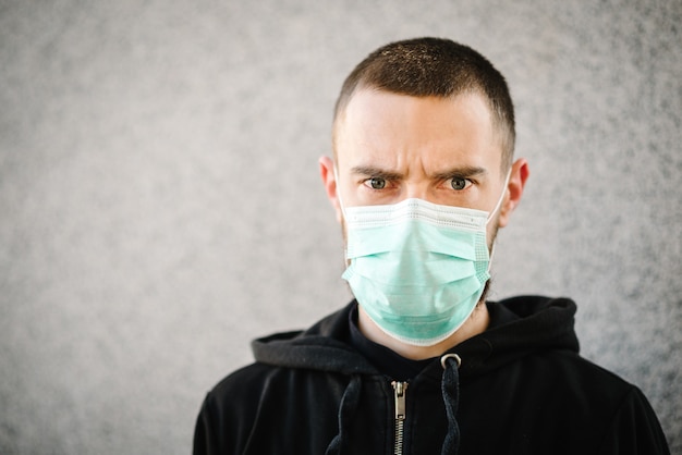 Coronavirus. Man wearing mask to prevent infection on a gray wall background, airborne respiratory illness such as flu, 2019-nCoV. Epidemic. Protect your health. Concept of quarantine. MERS-Cov.