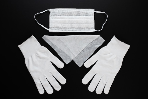 Coronavirus Mandatory remedy White antibacterial medical mask cleansing hand towel and gloves on a black background