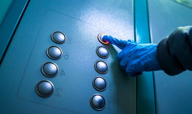 코로나바이러스 발병 손으로 고무 파란색 장갑을 끼고 엘리베이터 버튼을 누르면 위생 개념 박테리아 및 바이러스 예방 자기 보호