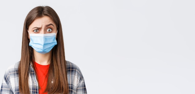 Coronavirus outbreak leisure on quarantine social distancing and emotions concept Confused young woman cant understand what happening look suspicious or surprised wear medical mask